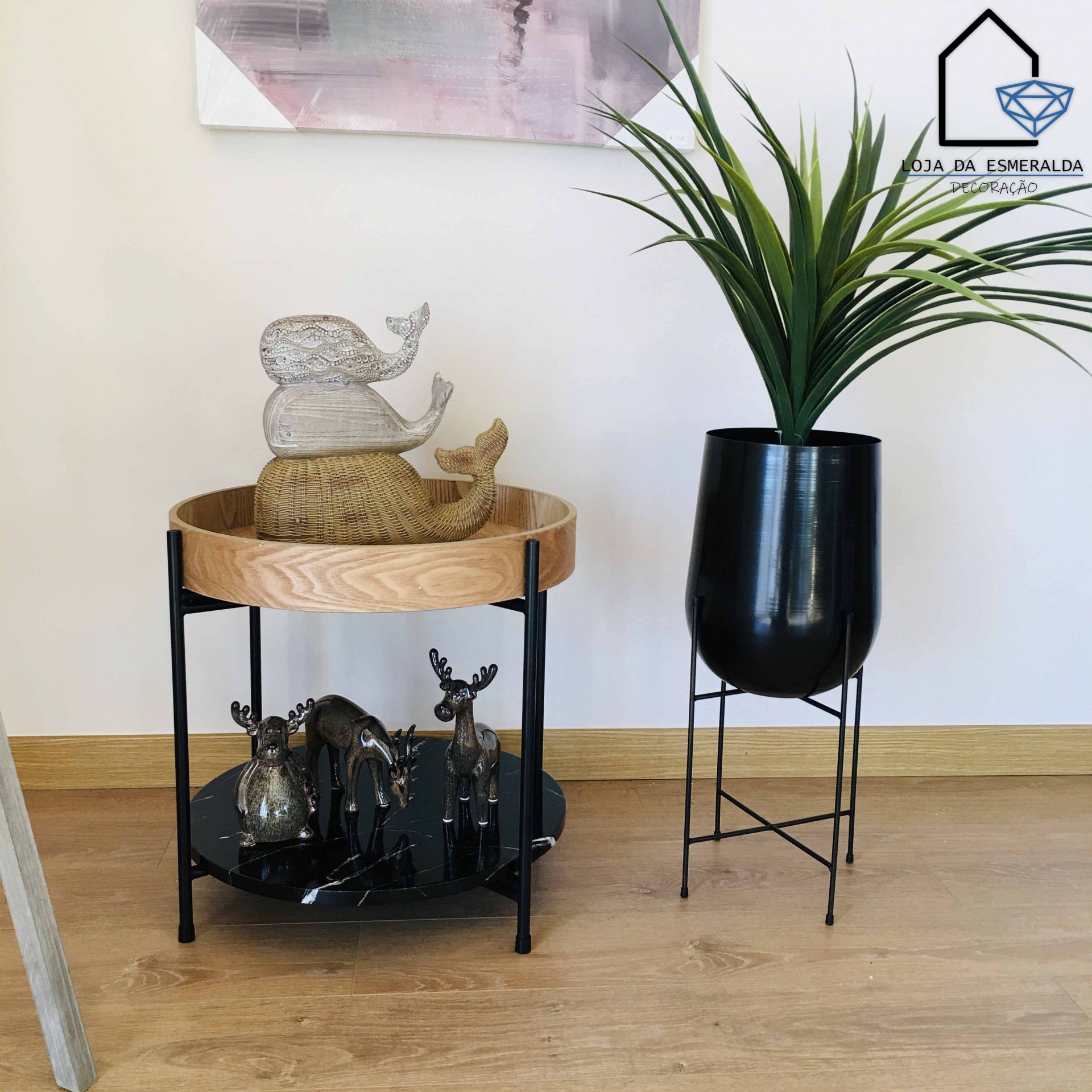 mesa auxiliar redonda com esculturas de baleias e veados, vaso preto com planta, chão de madeira