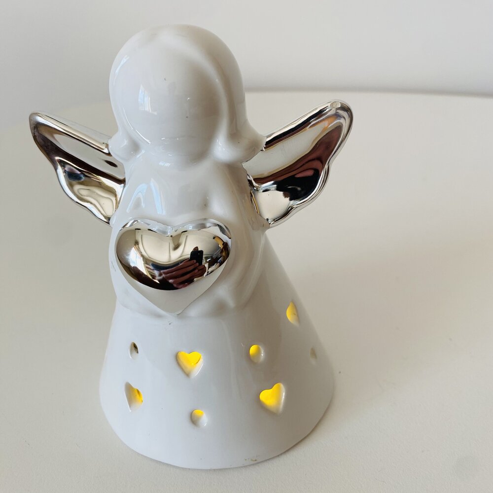 Anjo decorativo cerâmico branco com detalhes prateados e recortes em forma de coração iluminados