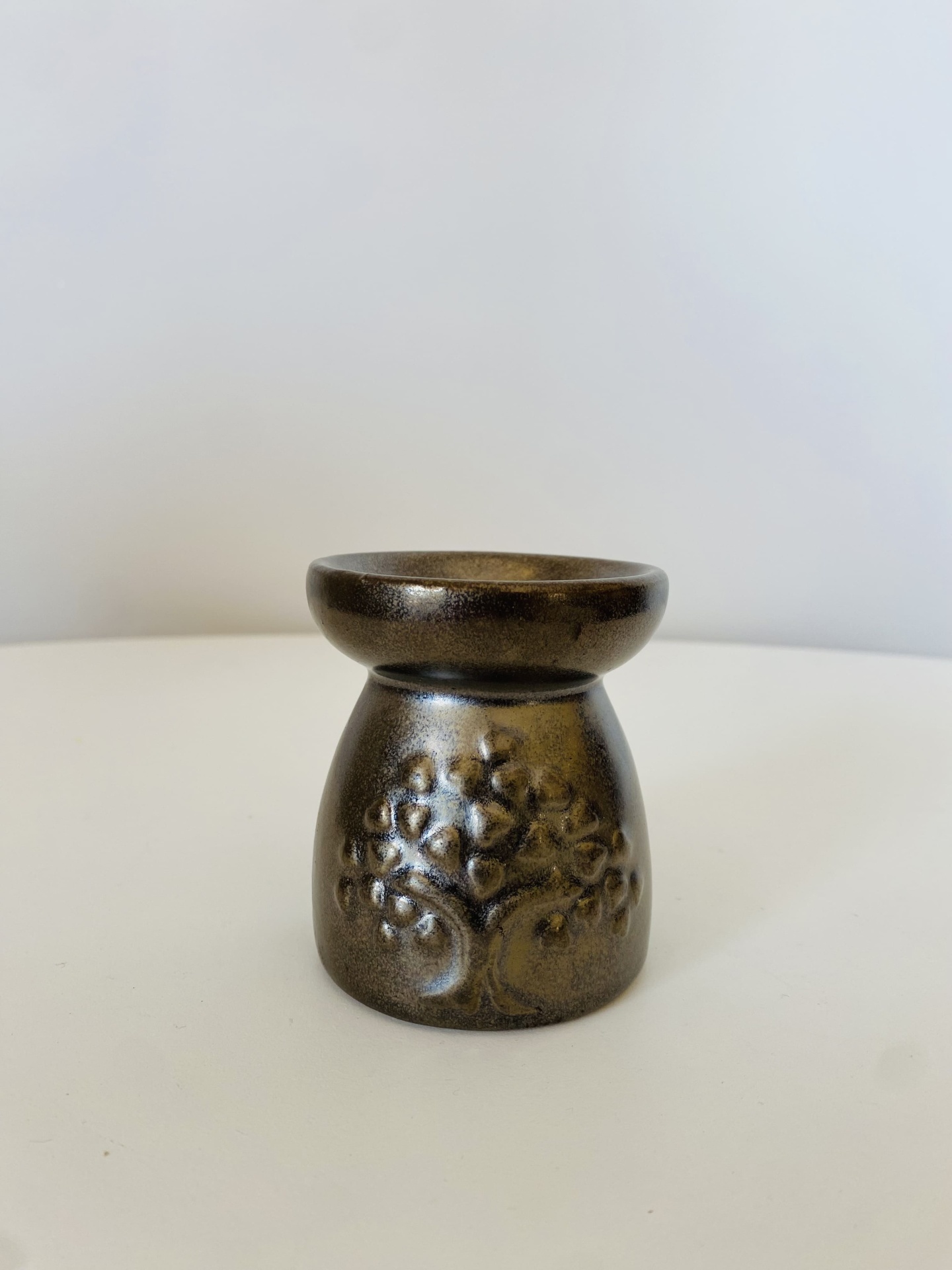 Velaira ou suporte decorativo em cerâmica castanha com relevo de árvore.