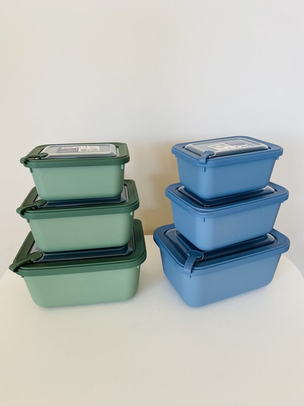 Caixas plásticas empilhadas verdes e azuis com tampas e fechos herméticos