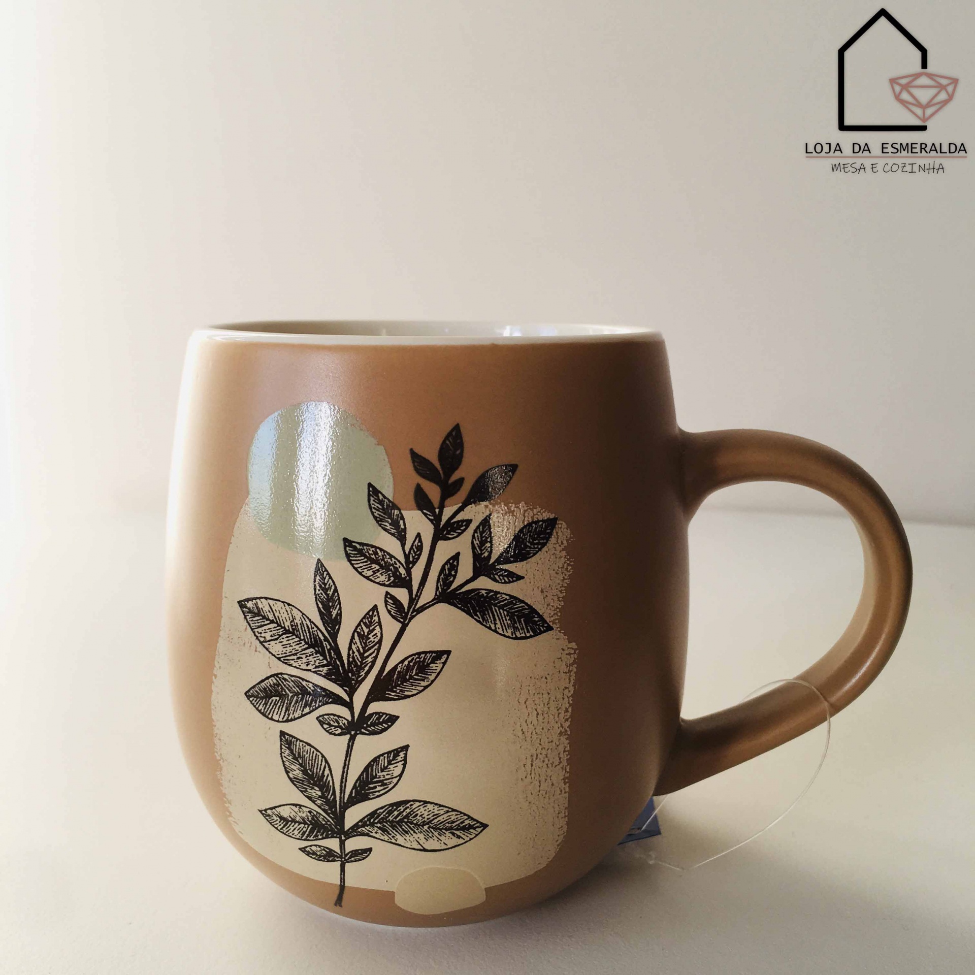 Caneca cinza castanha com desenho de folha e etiqueta de chá