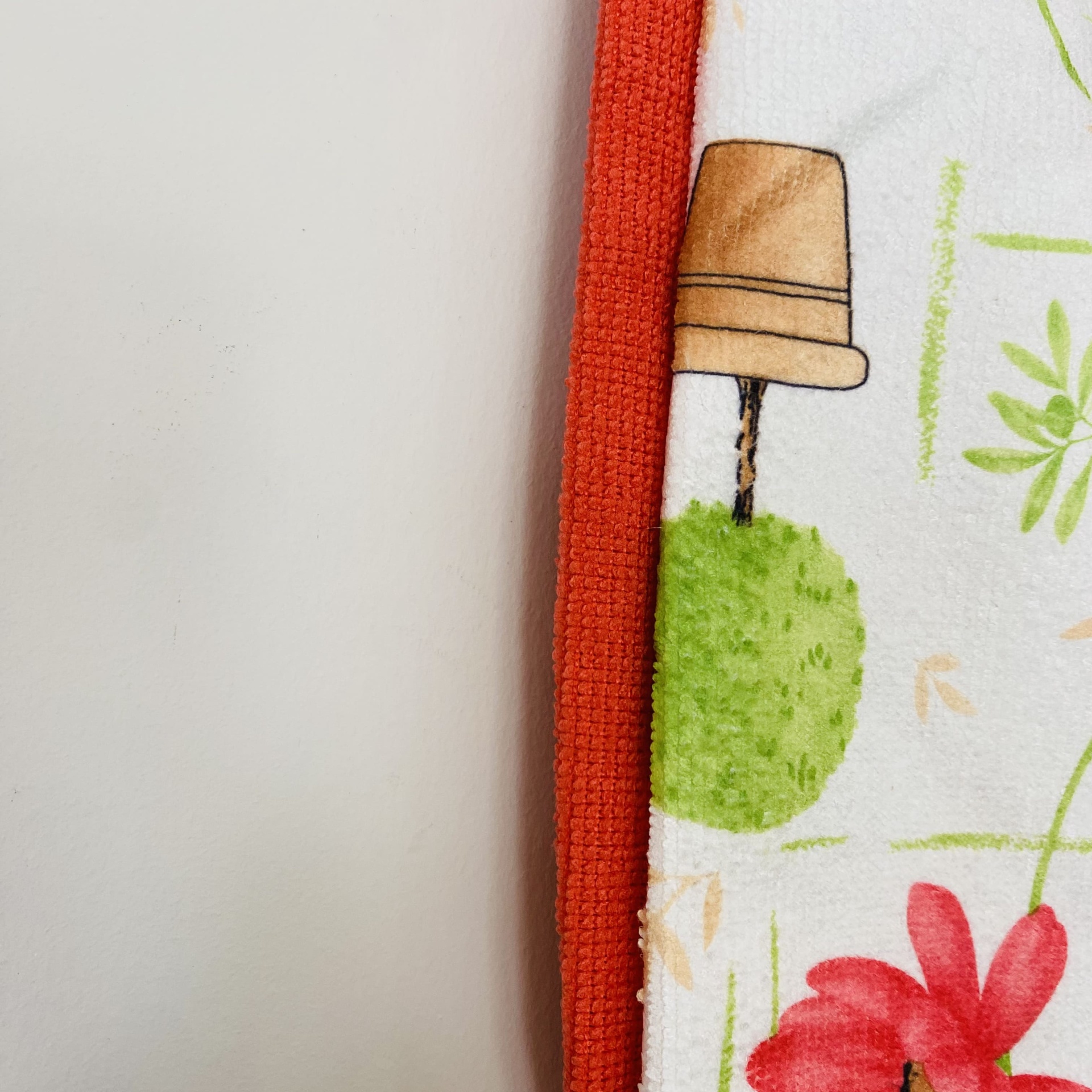 Toalha branca com flores e borda laranja texturizada sobre fundo branco