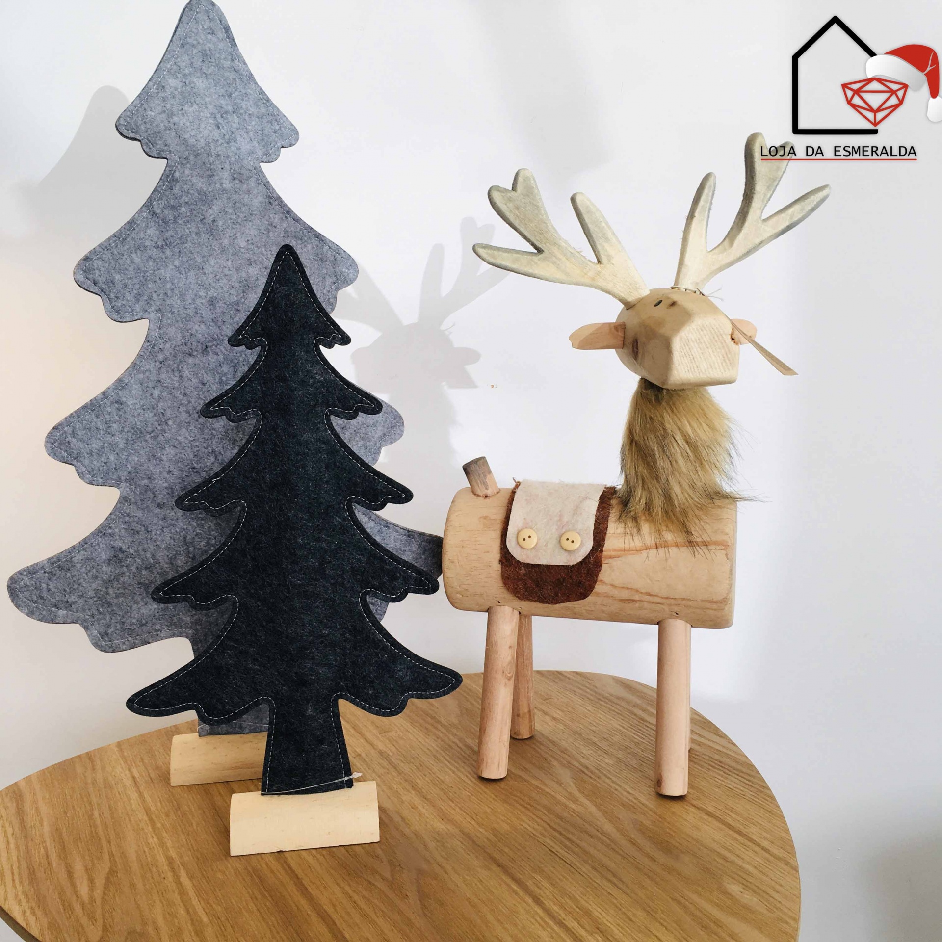 Decoração de árvores de feltro e veado de madeira num tampo de madeira.