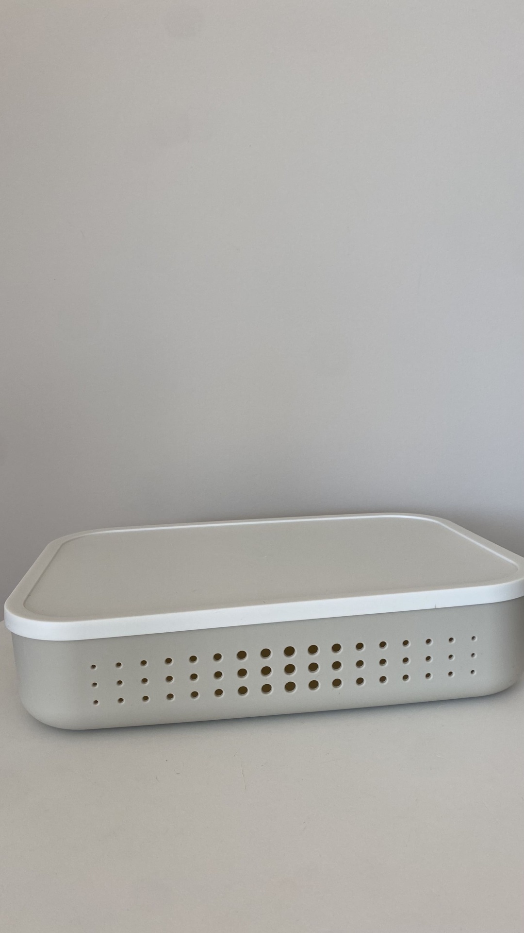 Caixa de armazenamento cinzenta com tampa branca e orifícios circulares