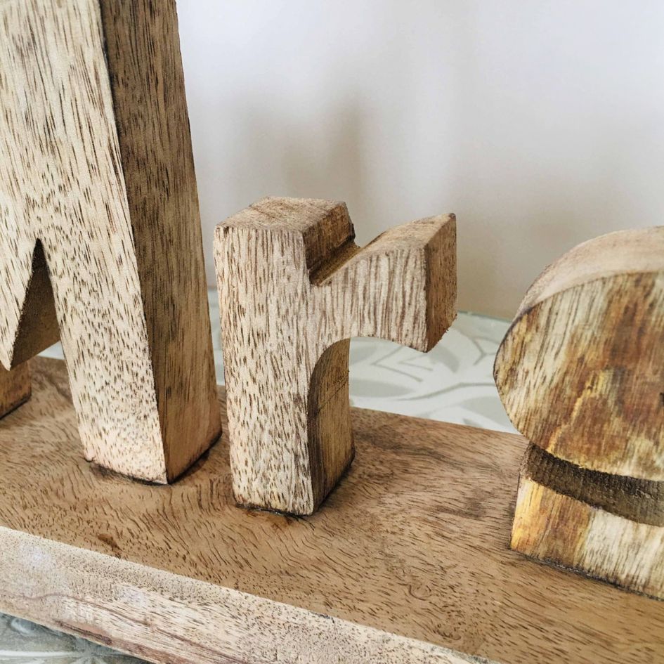 Peça decorativa em madeira com letras esculpidas e textura natural