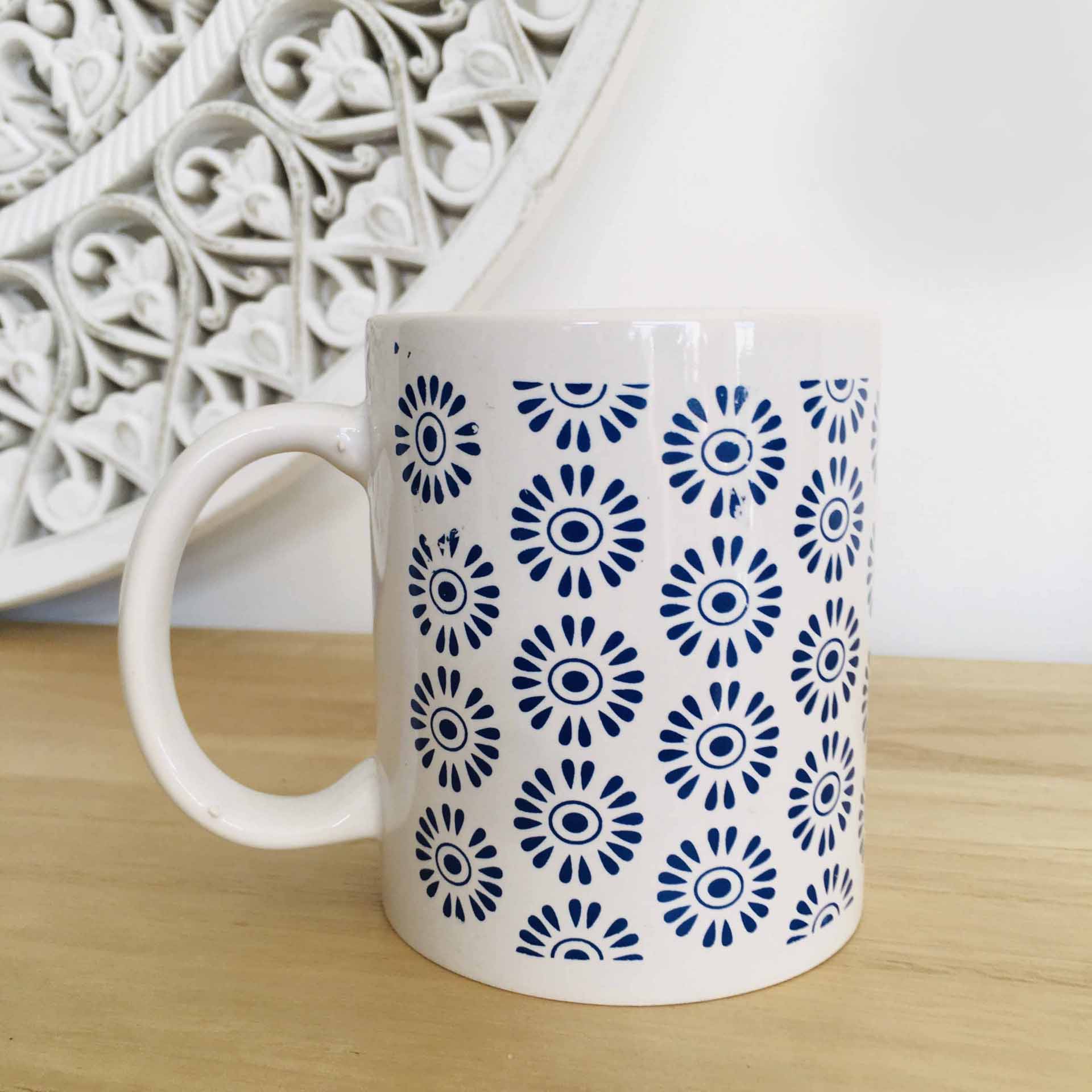 Caneca branca com padrão azul sobre superfície de madeira