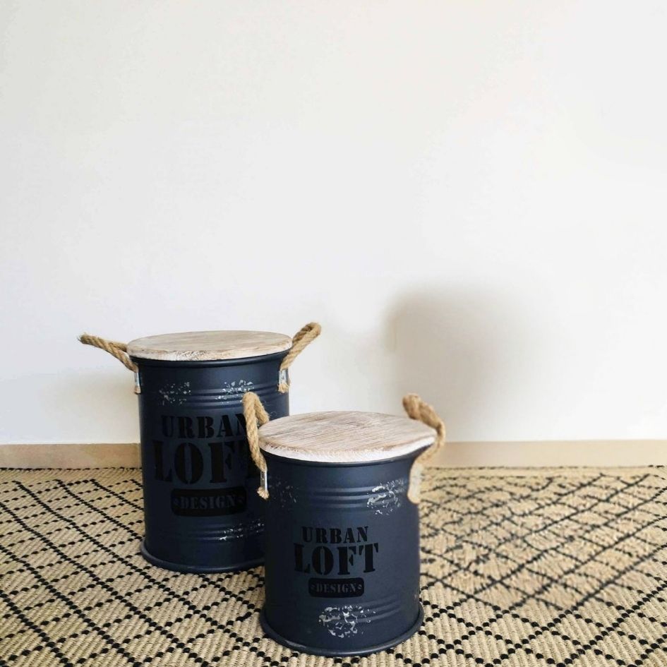 Tambores decorativos pretos com tampas de madeira e alças de corda sobre tapete geométrico