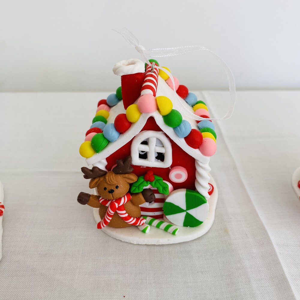 Casinha de Natal decorativa vermelha com detalhes coloridos e boneco de rena