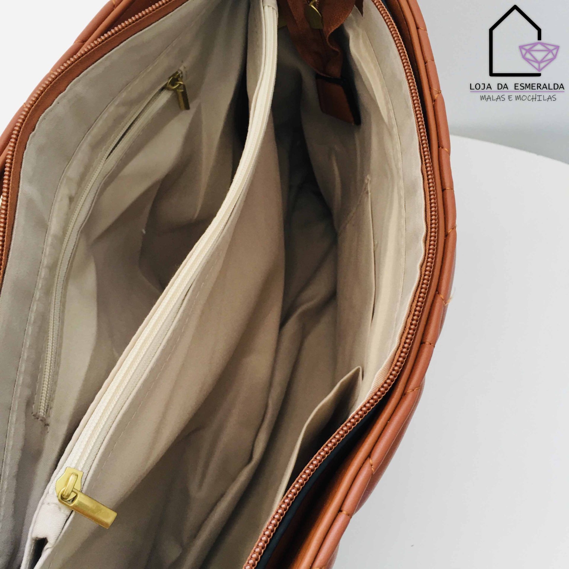 Bolsa castanha aberta mostrando interior bege com compartimentos e zíper
