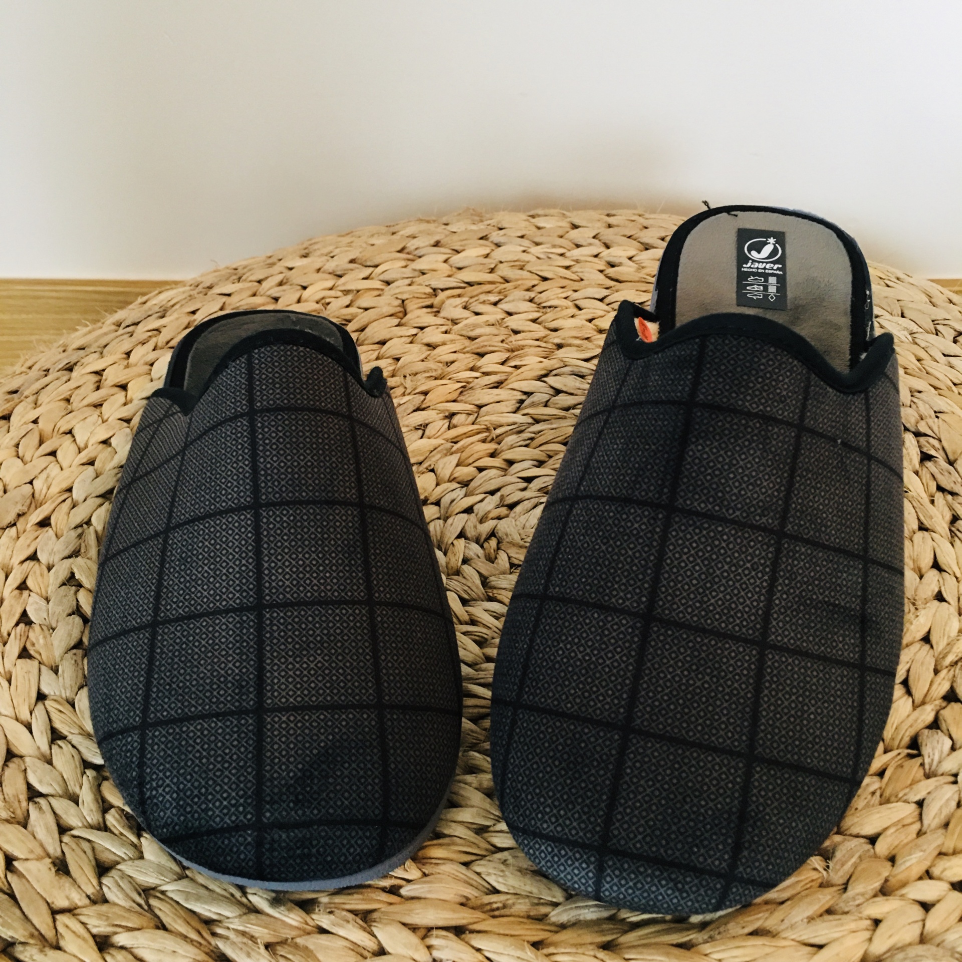 Chinelos pretos com padrão xadrez sobre base texturizada bege