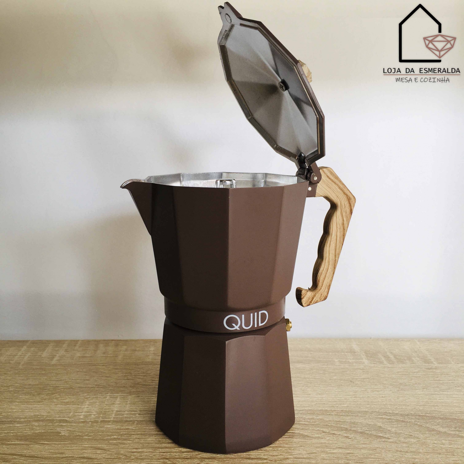 Cafeteira moka castanha com pega de madeira clara e tampa aberta sobre mesa de madeira
