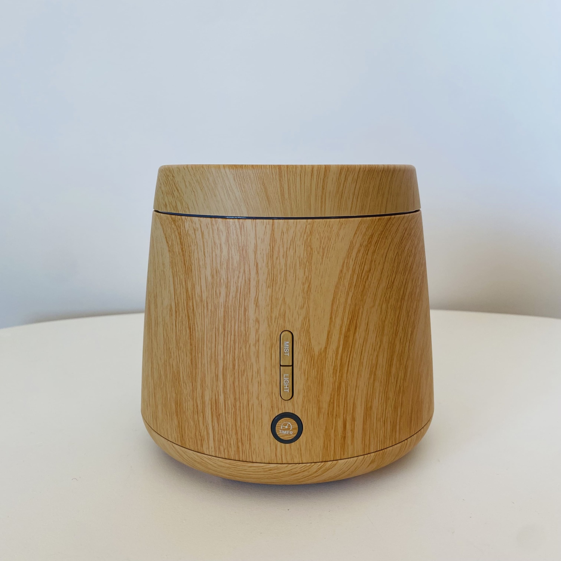 Difusor de aroma de madeira claro em superfície branca