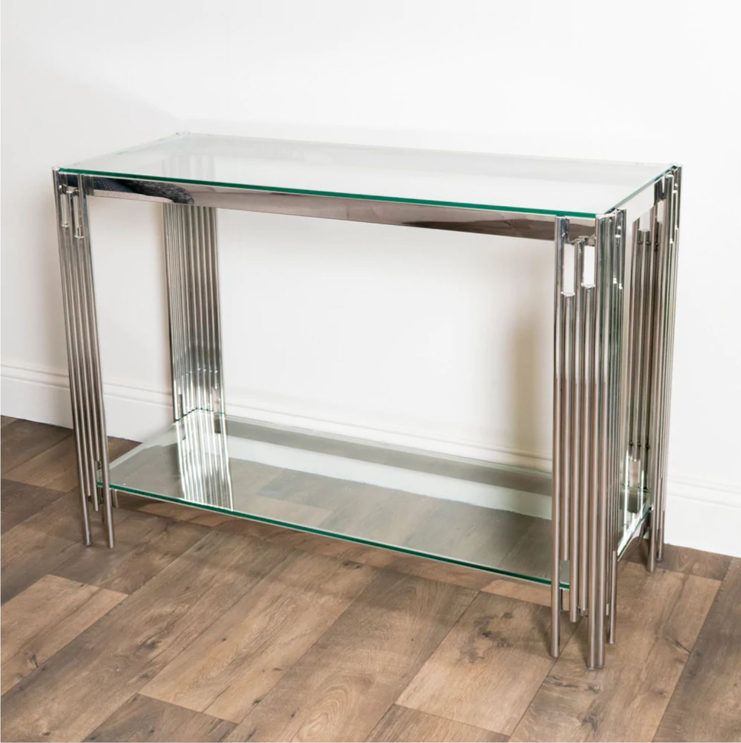 Consola em metal cromado e vidro transparente sobre chão de madeira