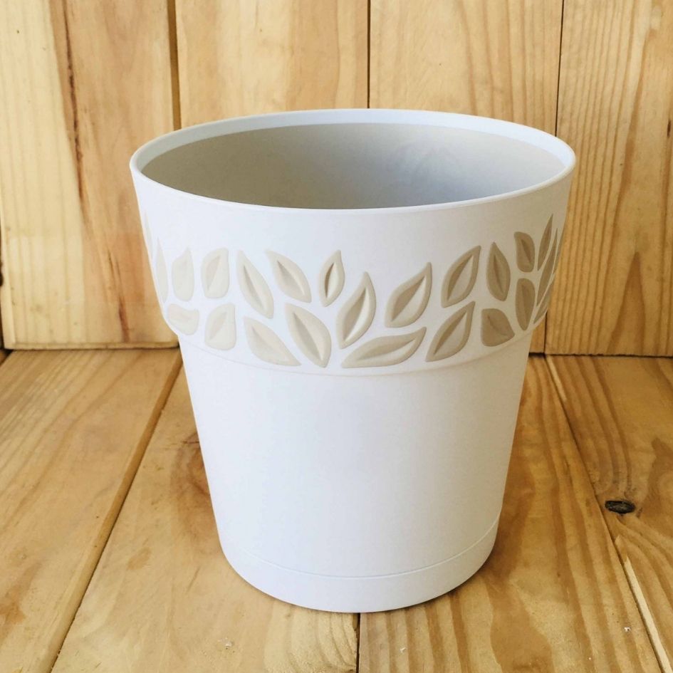Vaso de planta branco com padrão de folhas em relevo sobre madeira clara