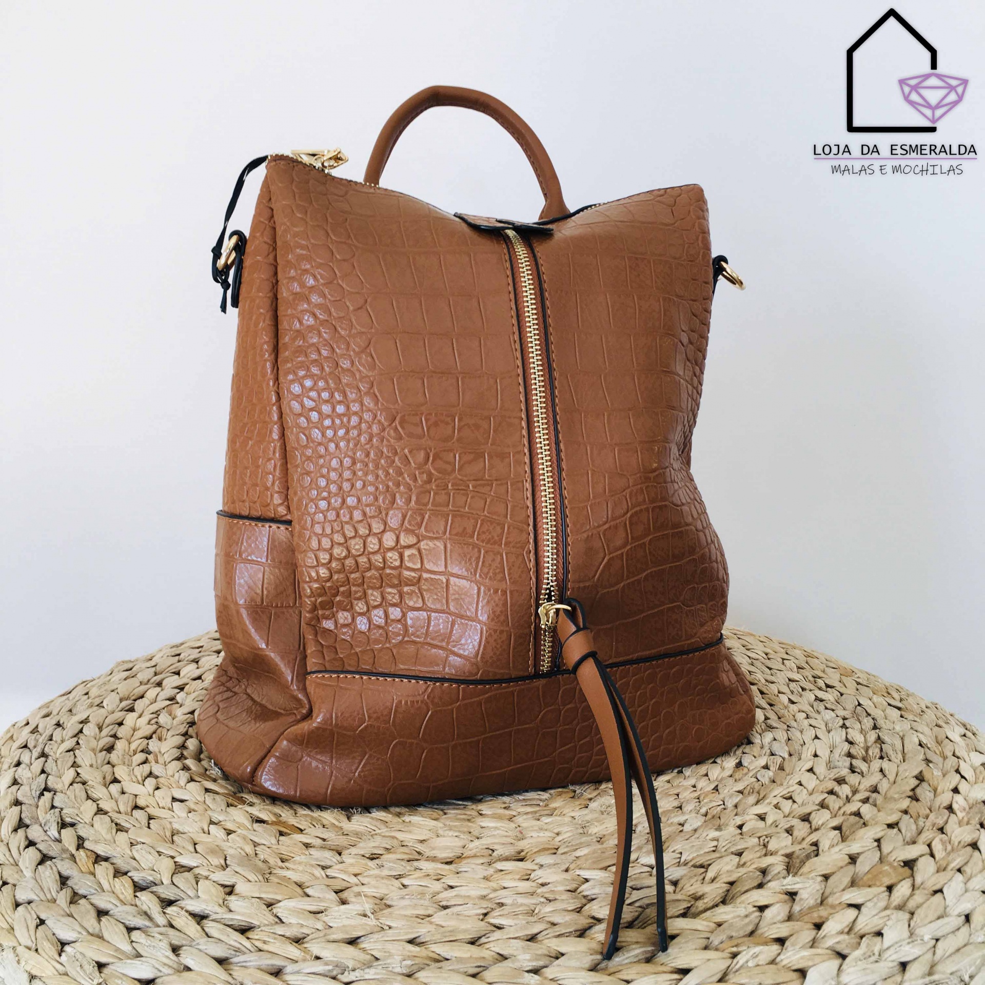 mochila castanha com padrão crocodilo em superfície redonda de fibras naturais