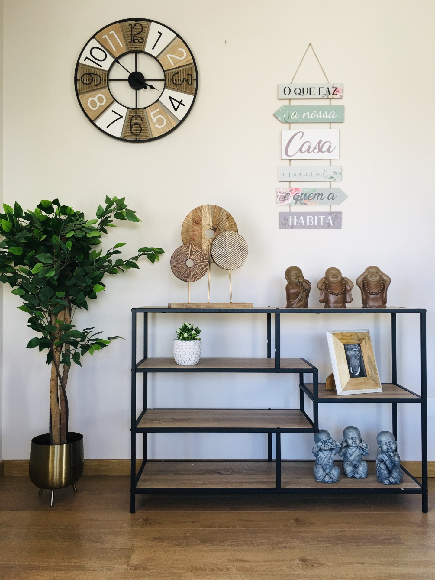 Relógio, frase decorativa, estante preta com prateleiras de madeira e decoração variada