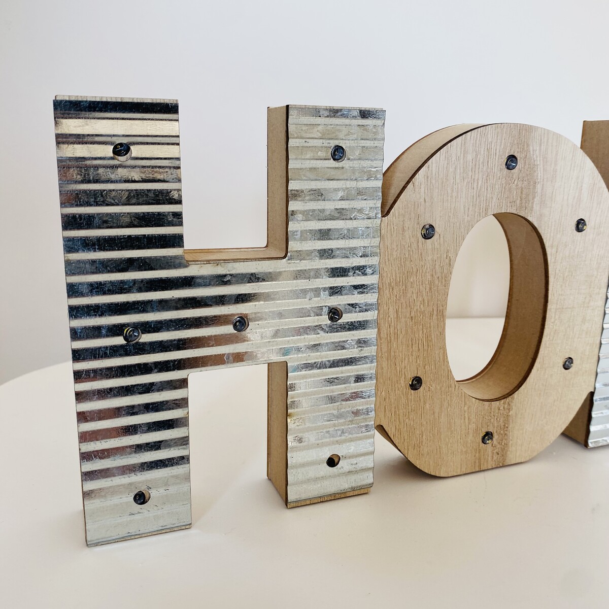 Letra decorativa H em madeira e metal prateado