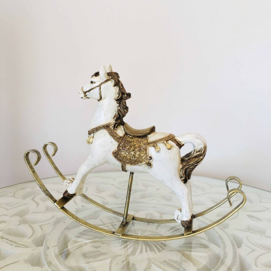Cavalo de baloiço decorativo branco com detalhes dourados numa base branca com padrão