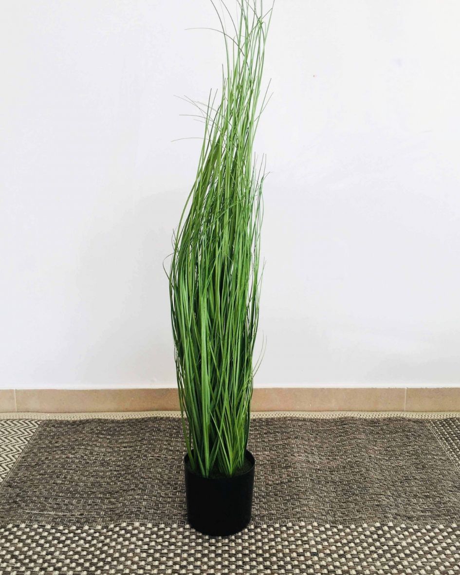 Planta artificial verde em vaso preto sobre tapete geométrico em ambiente interior claro