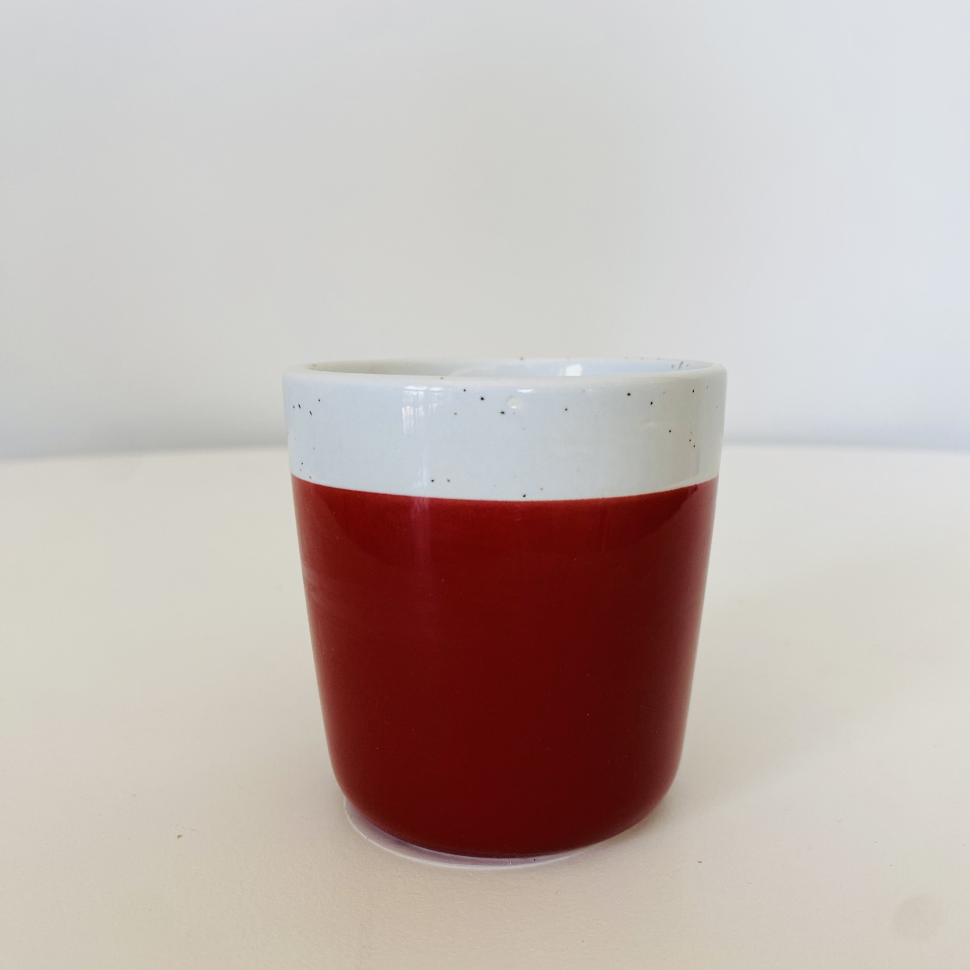 Copo de cerâmica branco e vermelho sobre superfície branca