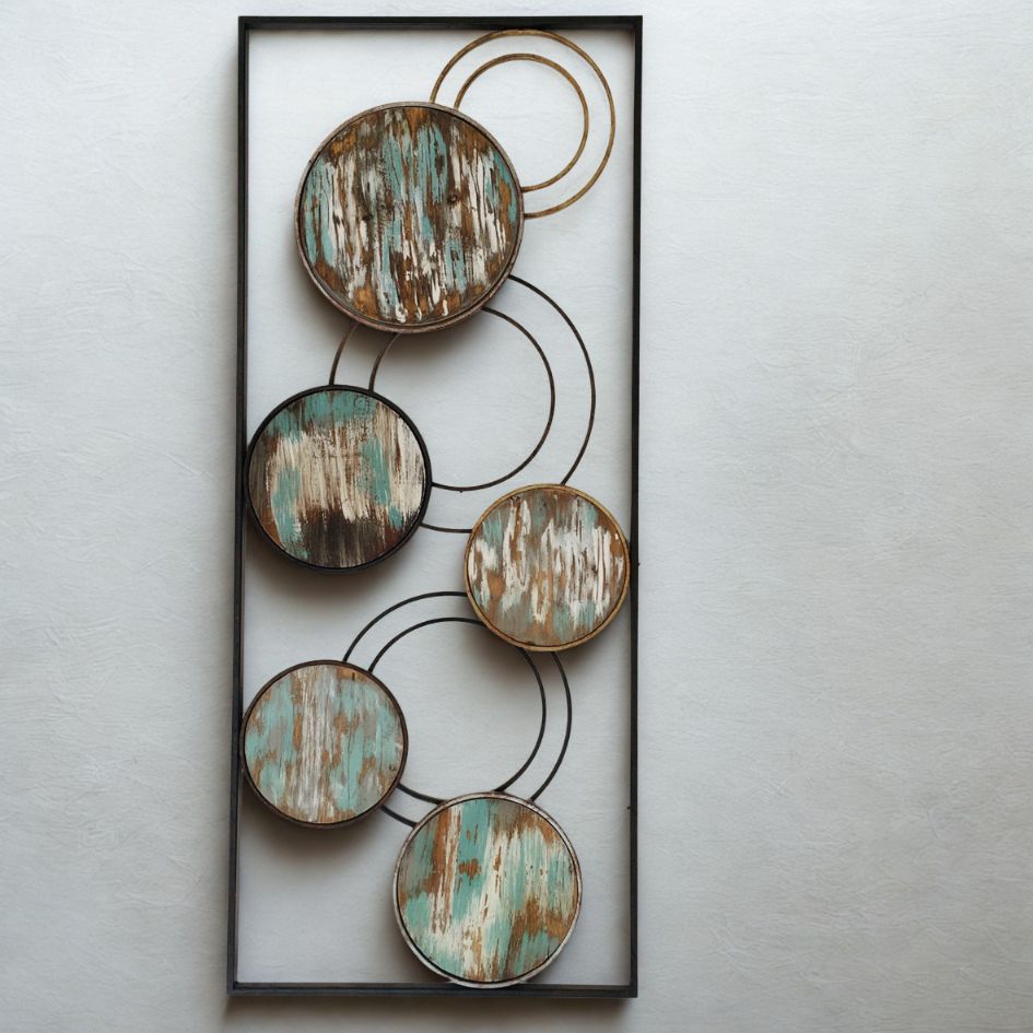 Elemento decorativo de parede com círculos de madeira pintada em tons desgastados dentro de moldura negra