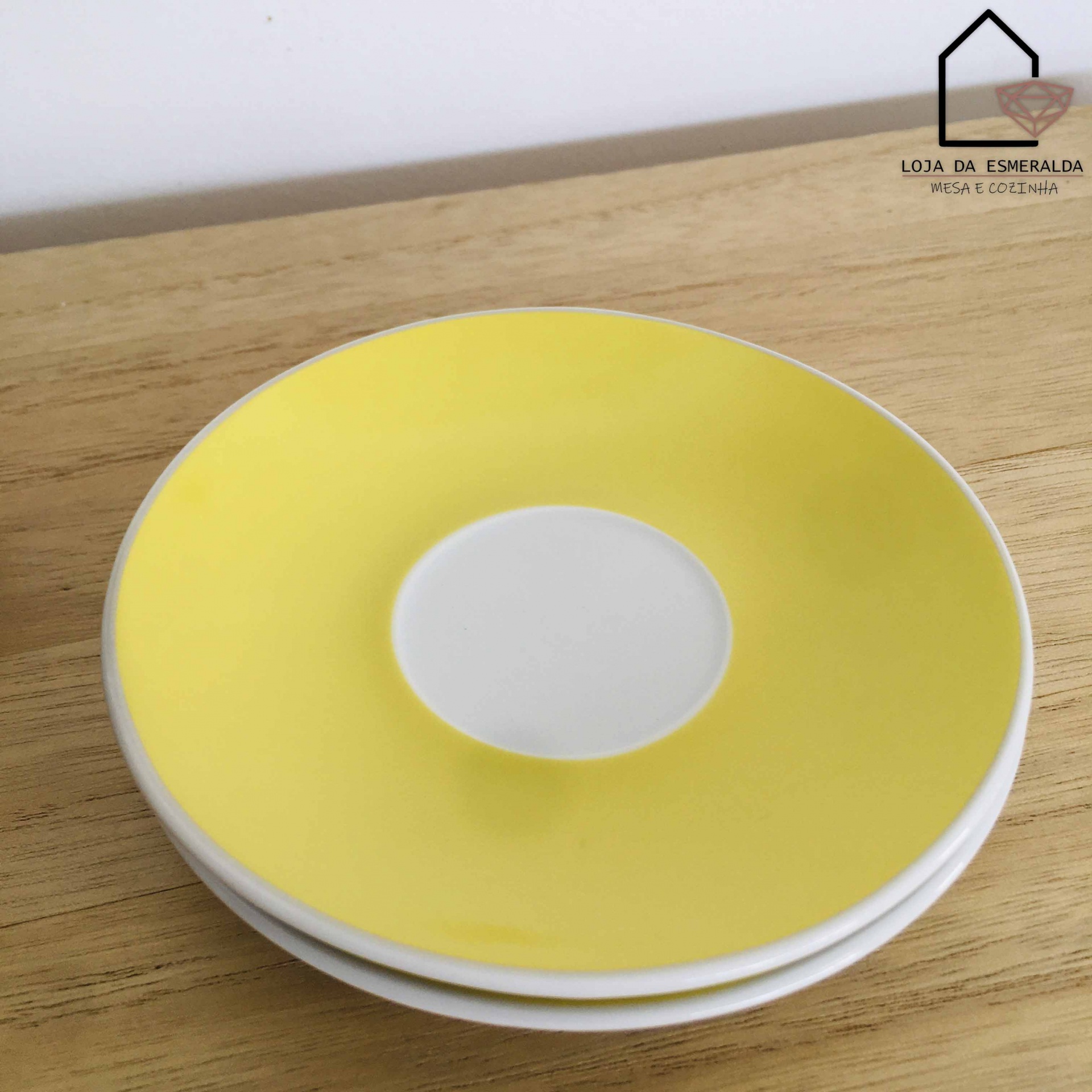 Três pratos pequenos brancos com borda amarela sobre mesa de madeira clara