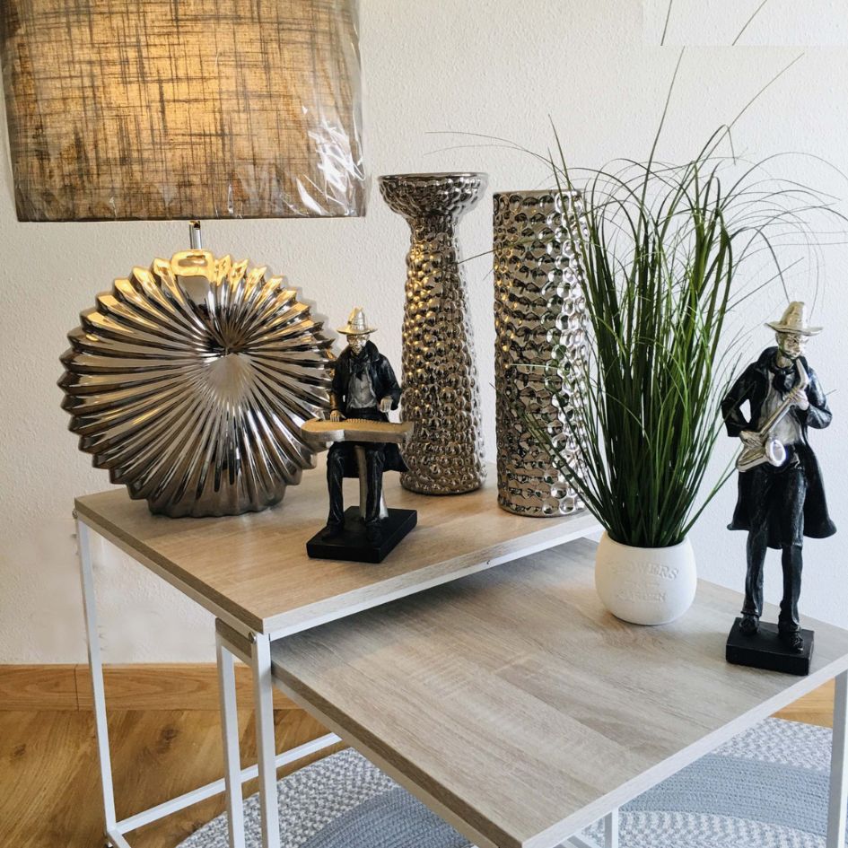 Mesa de apoio com decoração de vasos, plantas, estatuetas e lâmpada