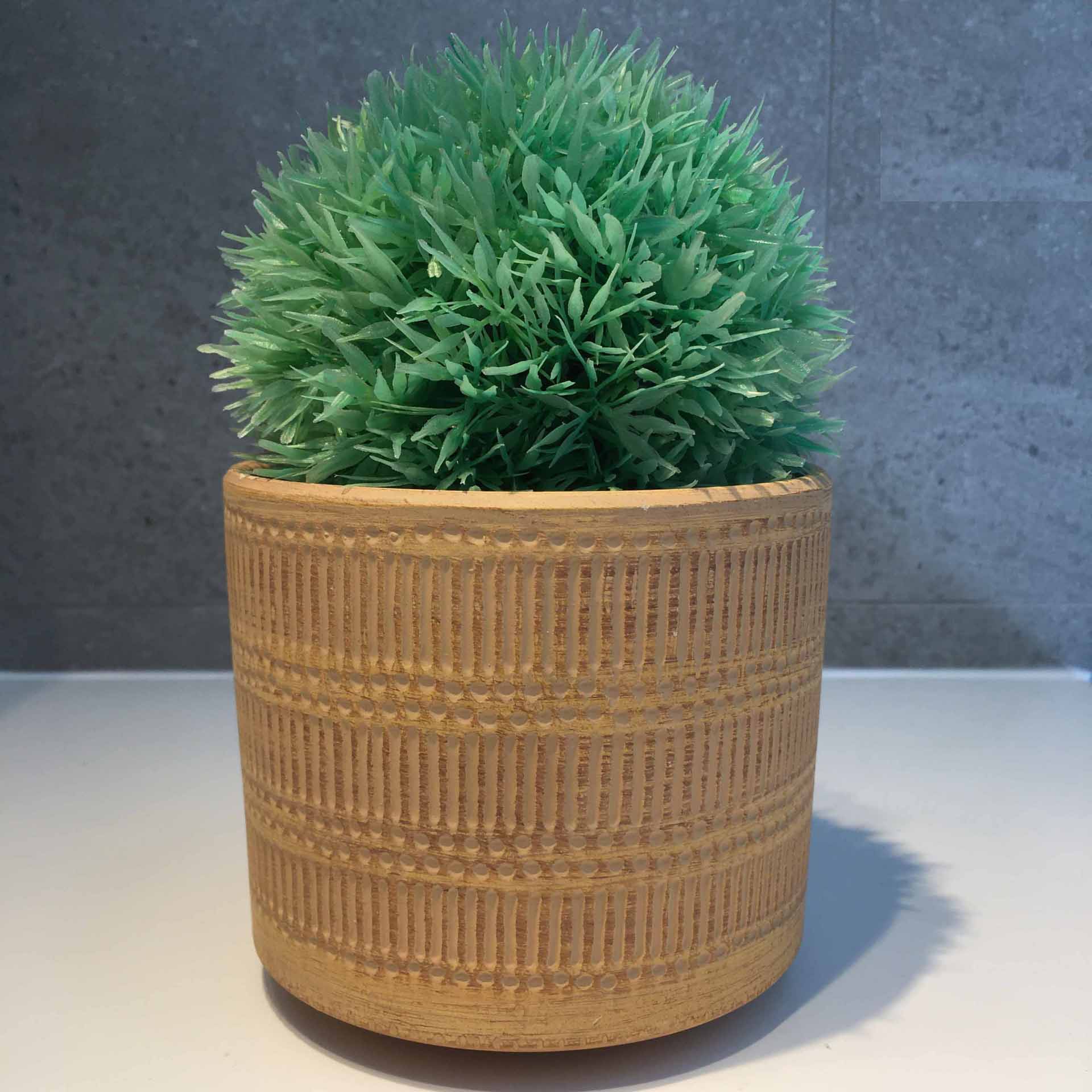 Vaso de cerâmica bege com planta artificial verde