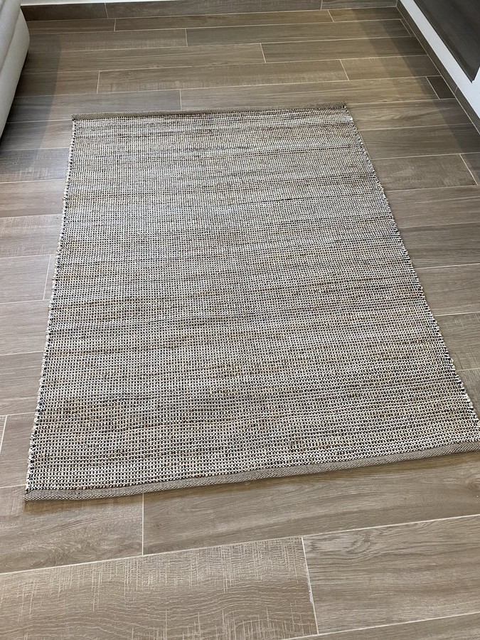 Tapete retangular bege e cinza sobre pavimento de madeira clara