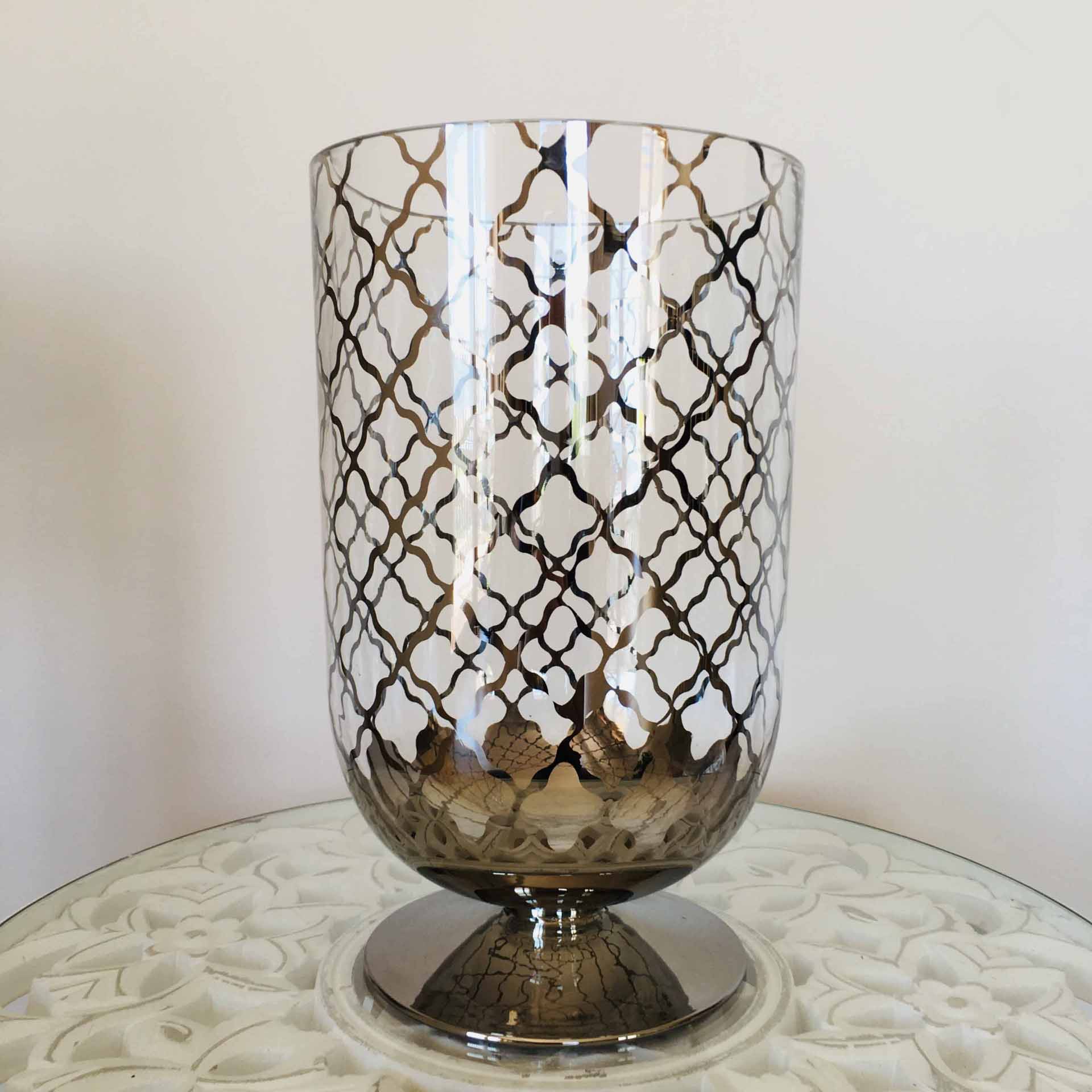 Vaso decorativo em vidro com padrão dourado sobre mesa branca com relevo