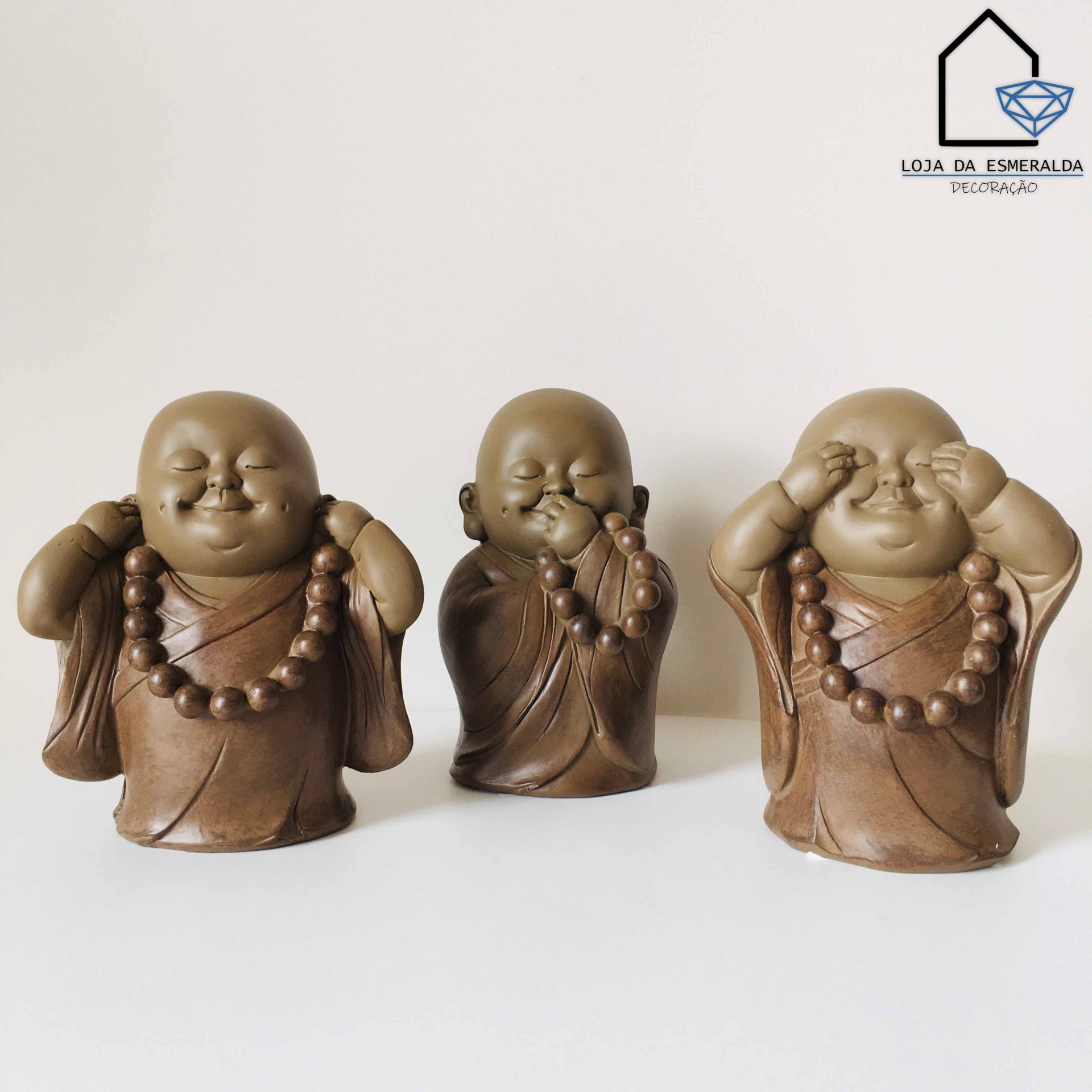 Três estatuetas de monges sorridentes em cerâmica marrom com contas grandes no pescoço