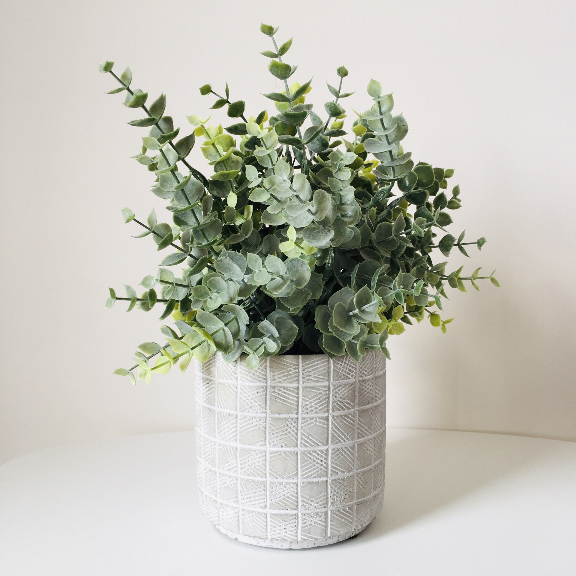 Vaso branco texturizado com planta artificial verde