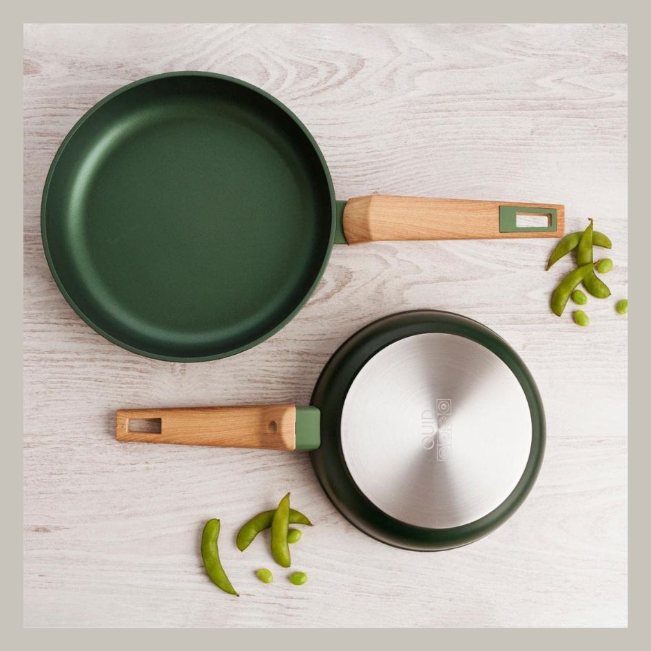 Duas frigideiras verdes com cabos de madeira sobre mesa clara com vagens verdes