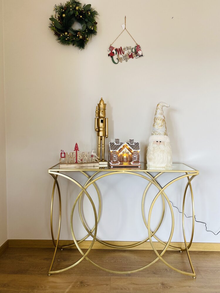 Mesa decorada de Natal com castanheiro dourado, casa iluminada, figura de Papai Noel e guirlanda na parede