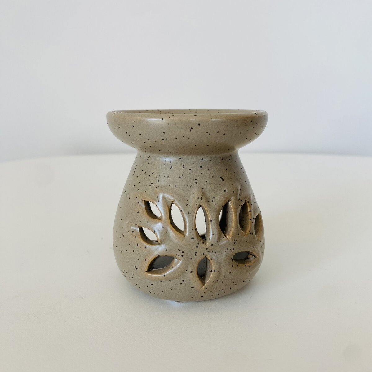 Frasco em cerâmica bege com recortes em forma de folhas