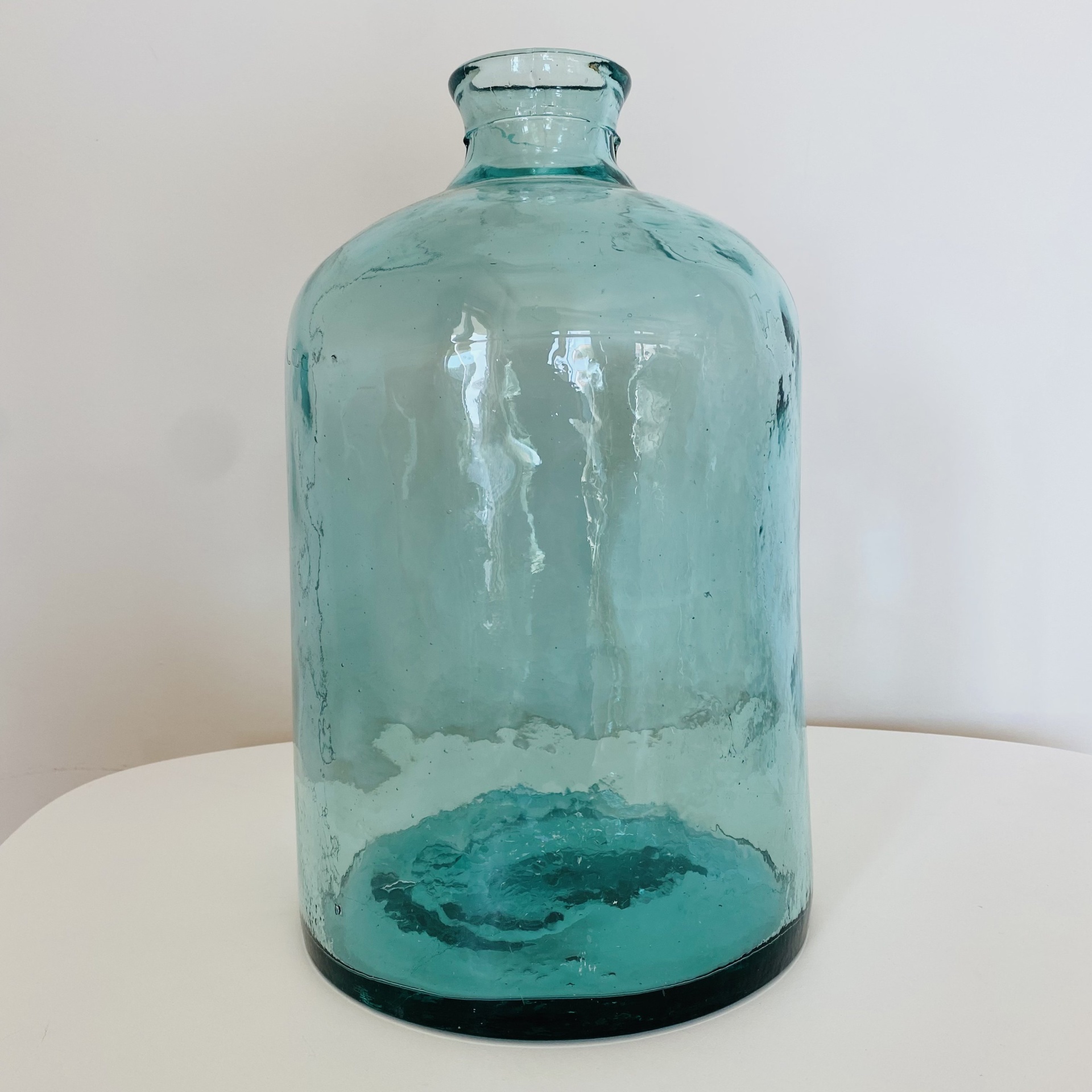 frasco de vidro azul esverdeado translúcido em superfície branca