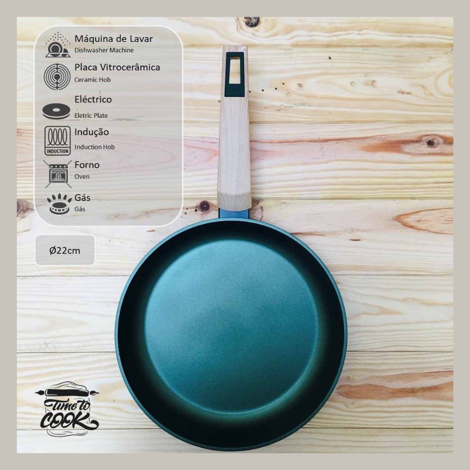 Frigideira azul com cabo de madeira sobre mesa de madeira