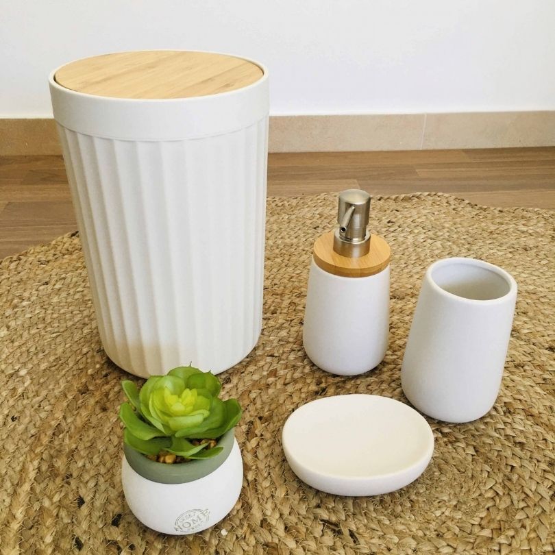 Conjunto de acessórios de casa de banho em cerâmica e madeira sobre tapete de ráfia