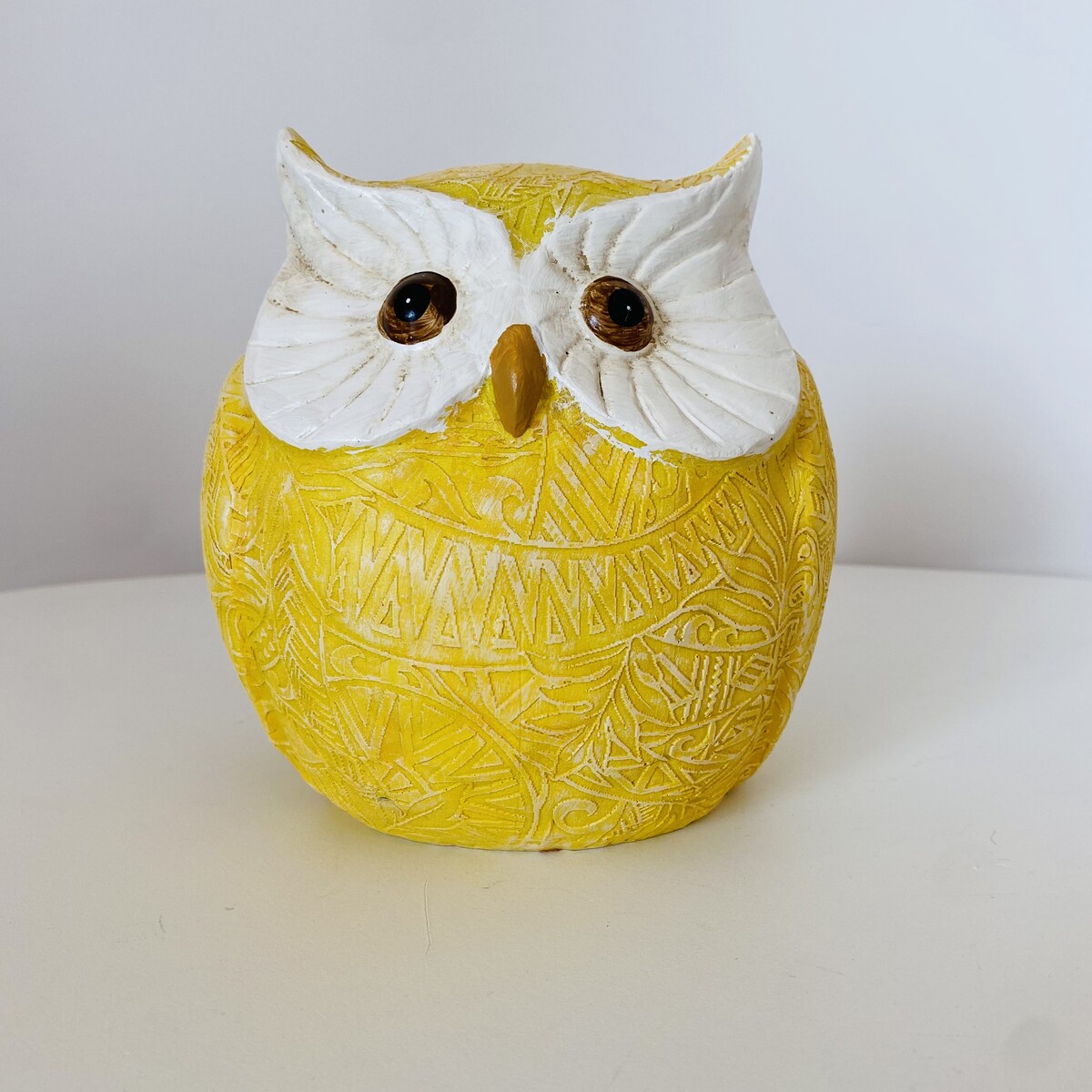 Coruja decorativa amarela com rosto branco e olhos castanhos