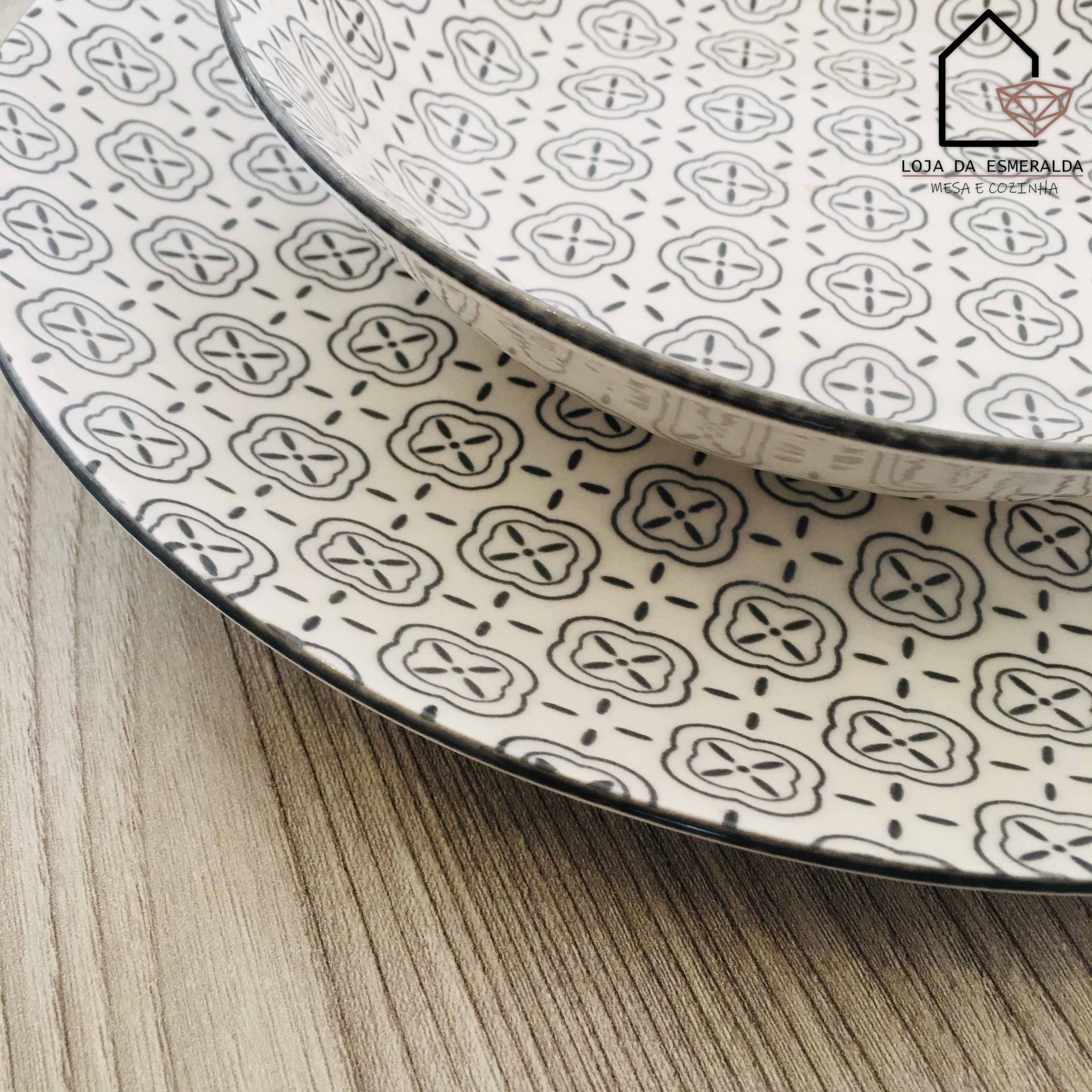 Pratos decorativos brancos com padrão geométrico preto e borda preta sobre madeira clara