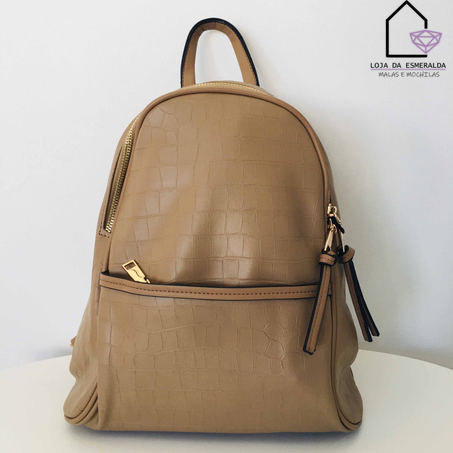Mochila bege com padrão de crocodilo e fechos dourados sobre superfície branca