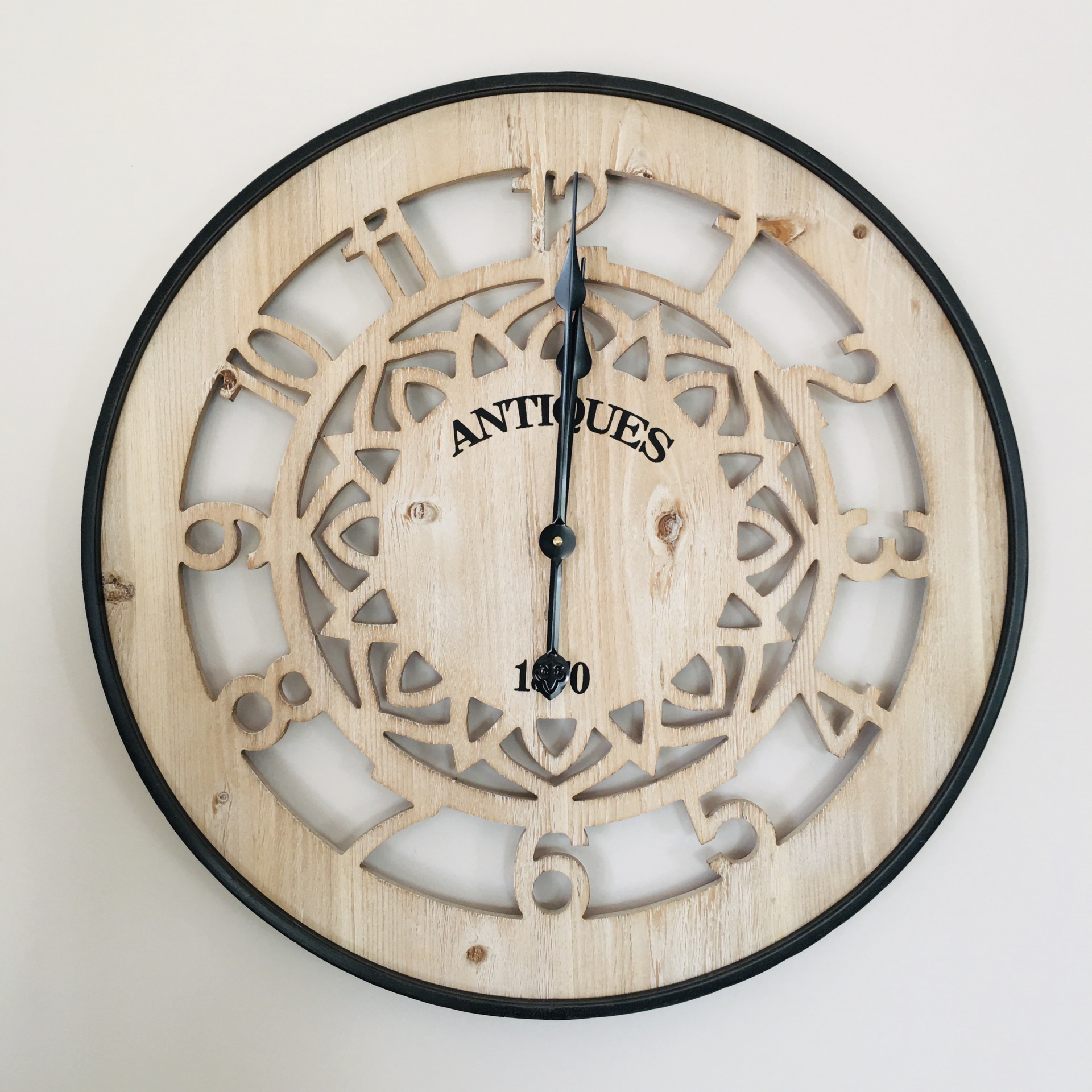 Relógio de parede em madeira clara com padrão geométrico e texto 'ANTIQUES 1870'