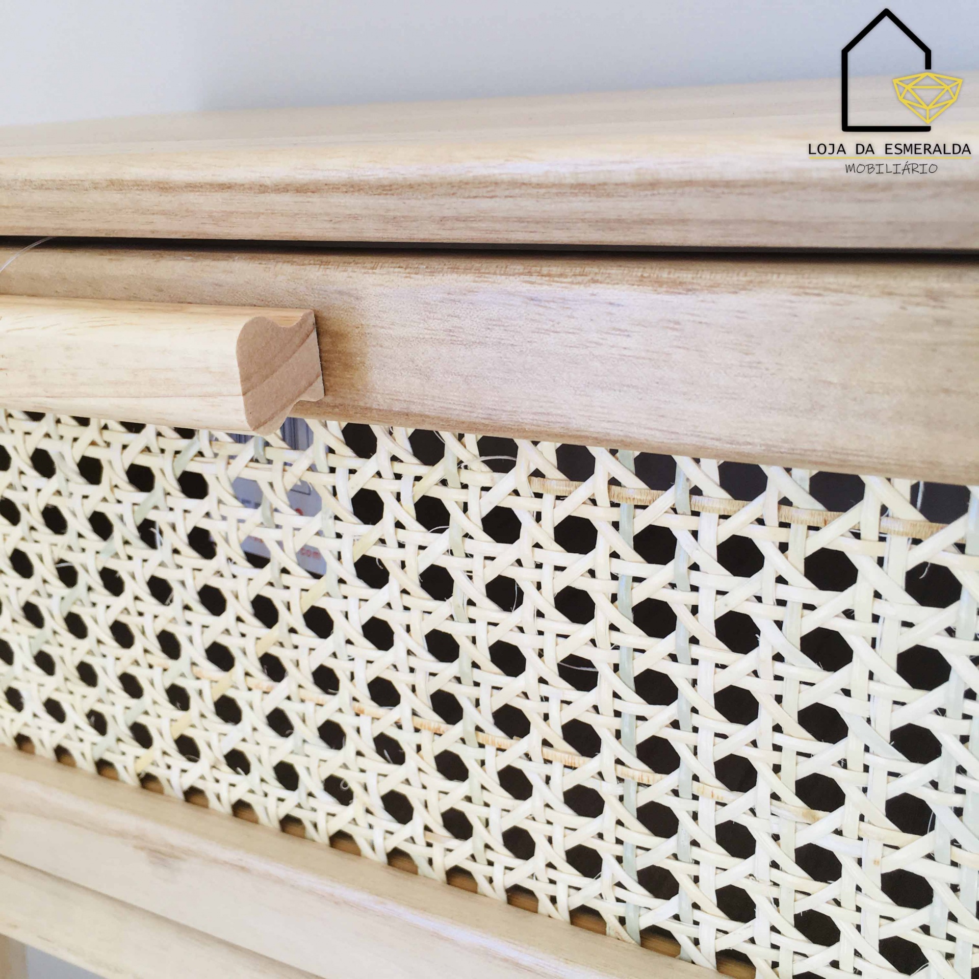 Móvel madeira clara com gaveta de padrão trançado bege e puxador de madeira, logo Loja da Esmeralda no canto superior direito