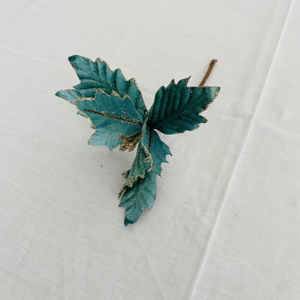 Folha decorativa artificial verde com glitter dourado sobre fundo branco.