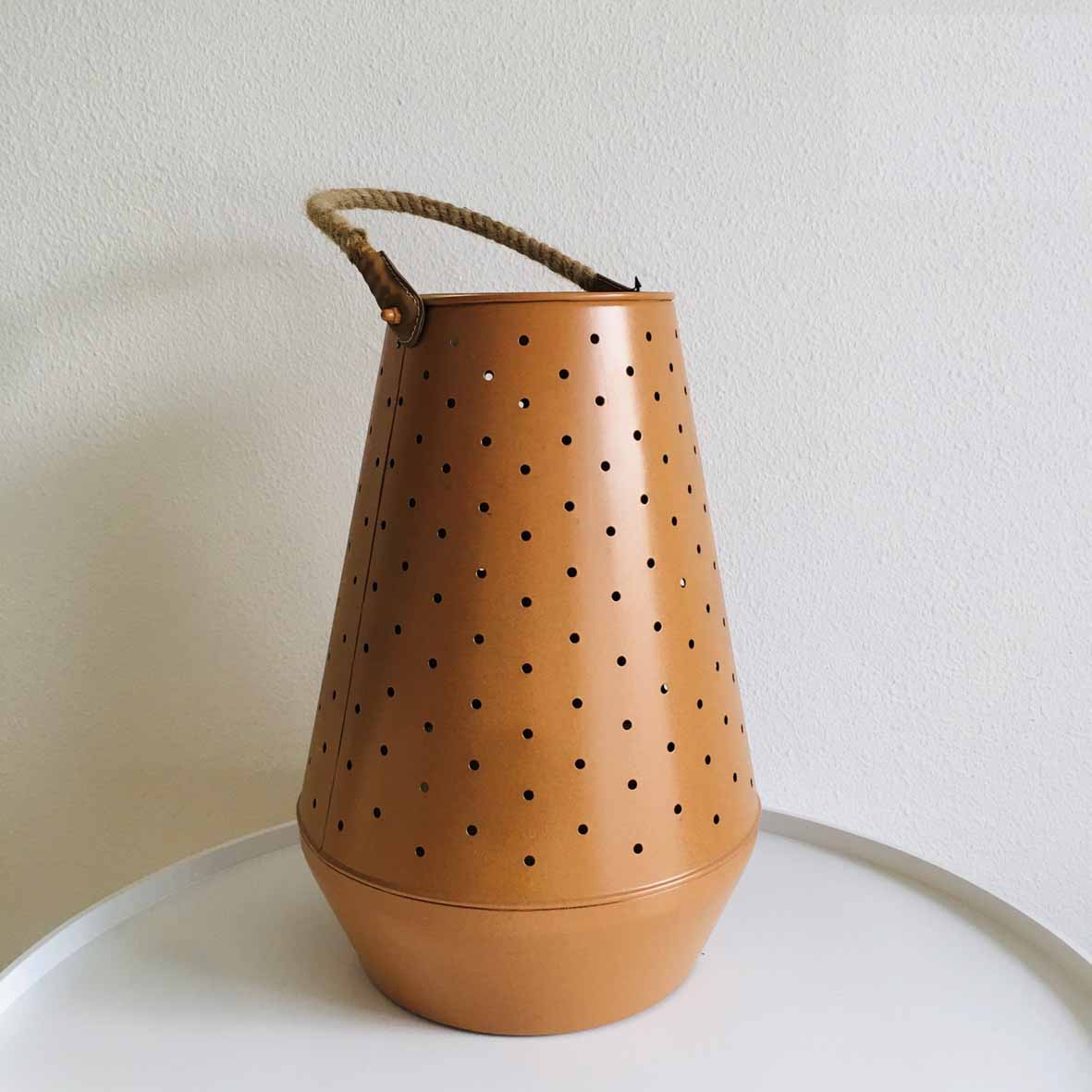 Lanterna castanha em metal com furos circulares e pega de corda