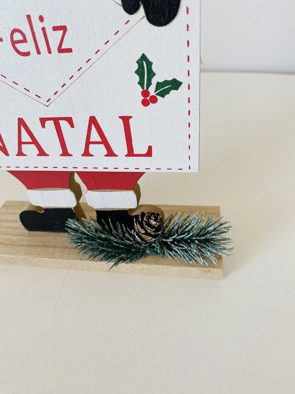 Placa decorativa de Natal em madeira com texto Feliz NATAL e decoração com pinha e ramo de pinheiro