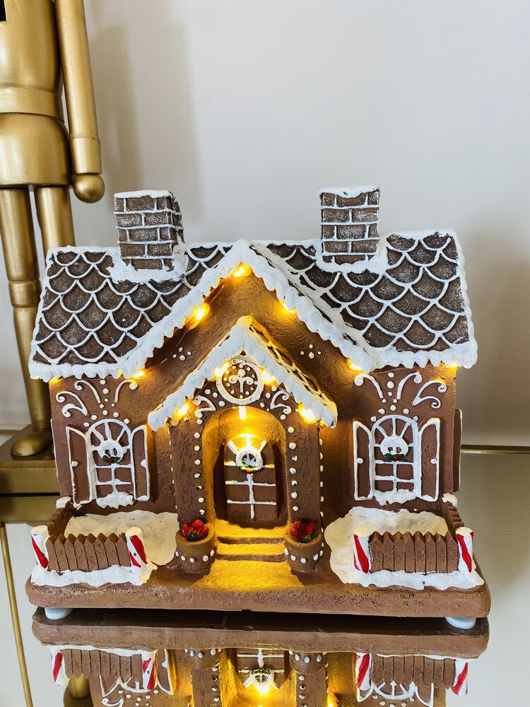 Casinha decorativa estilo gingerbread com luzes LED amarelas, detalhes em branco, castanho e vermelho.