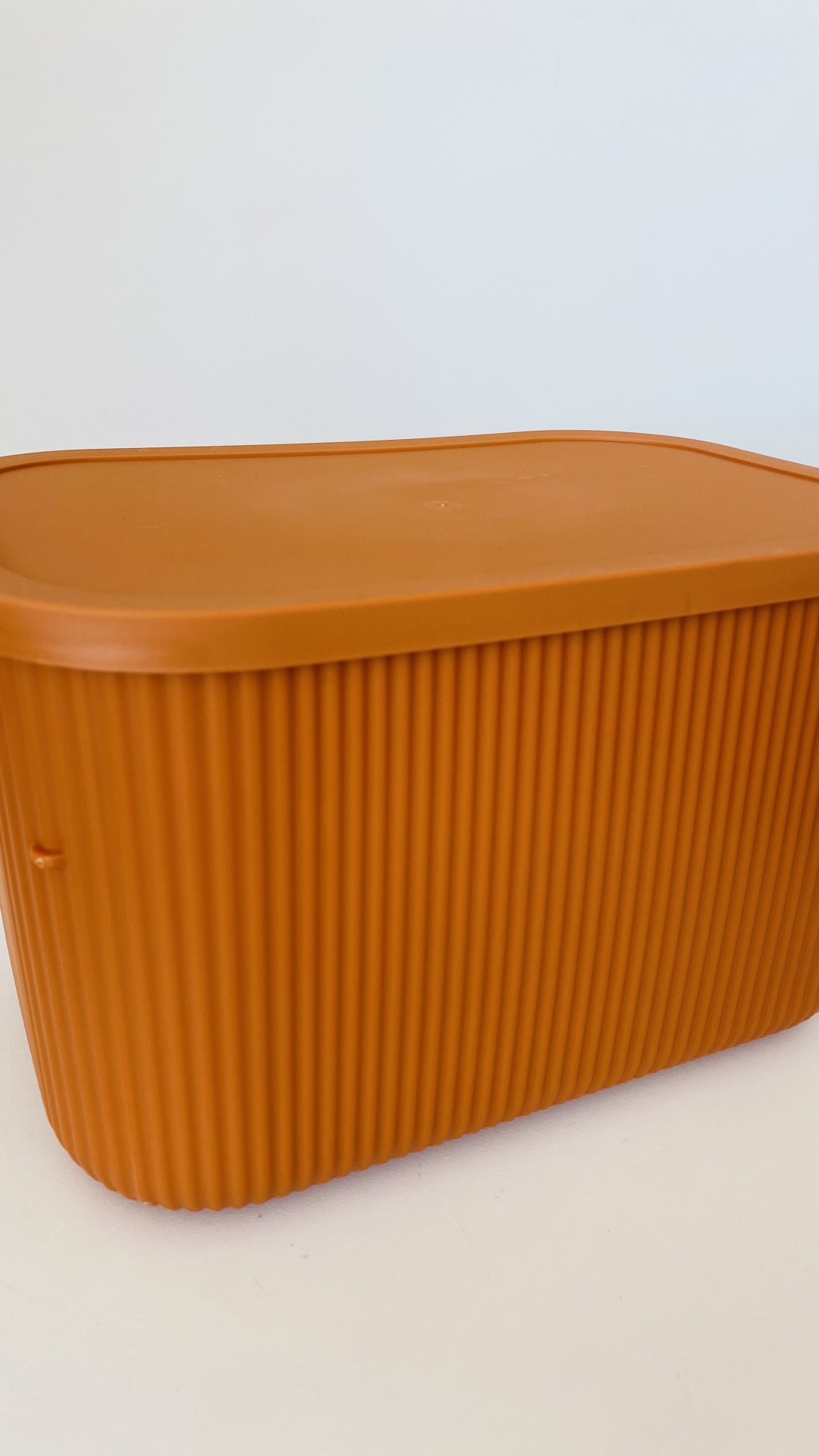 Caixa retangular de plástico laranja com tampa e textura vertical
