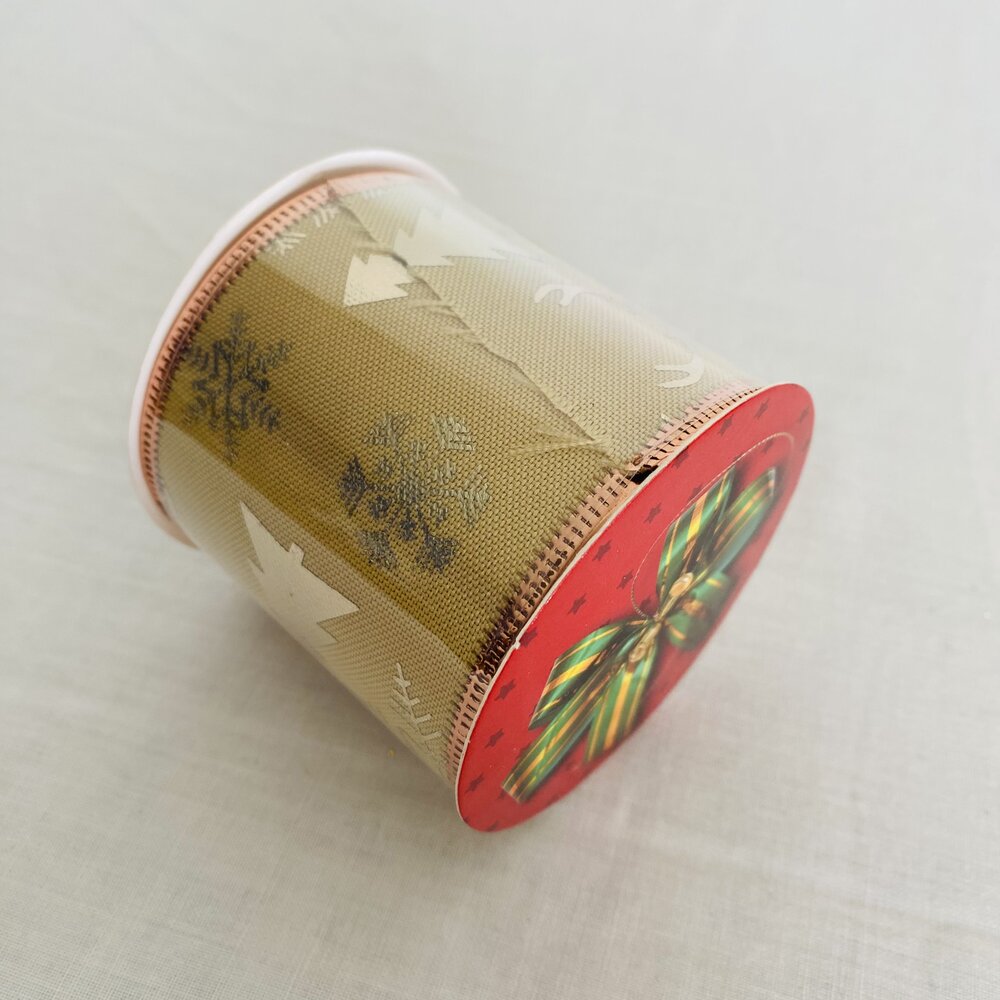 Rolo de fita decorativa bege com flocos de neve e estrelas, com extremidade vermelha e laço xadrez