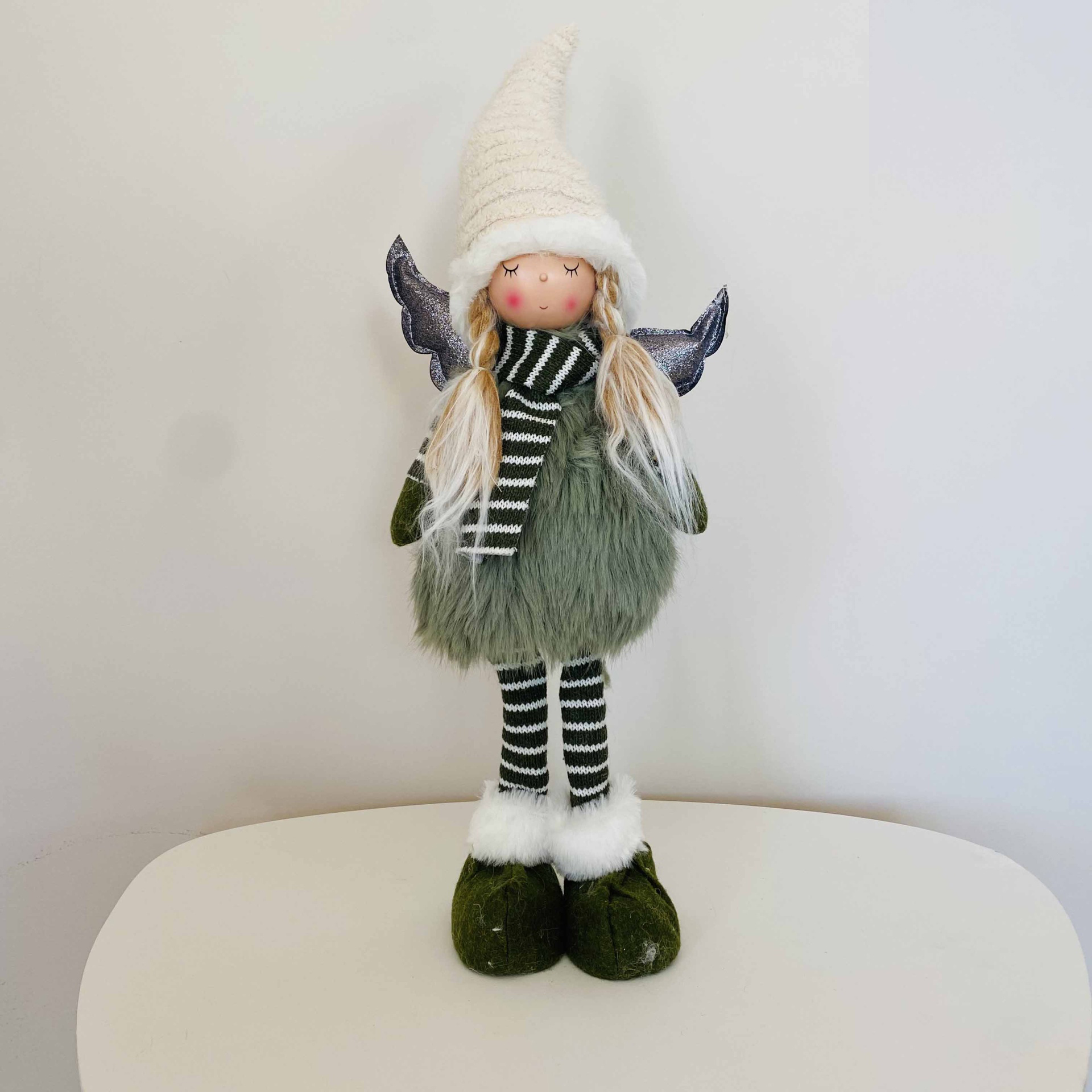 Boneca decorativa com vestido verde, perna listrada, chapéu branco e asas cinzentas